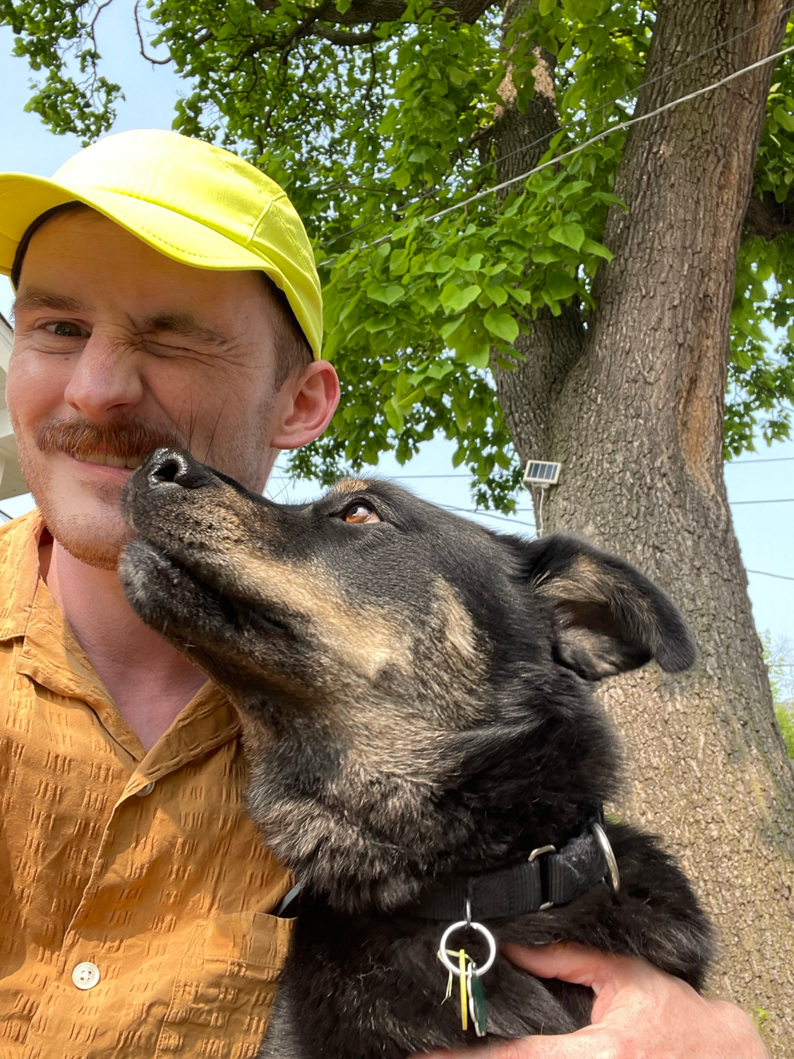 Matt and Donut sitting side by side; donut is licking matty's nose