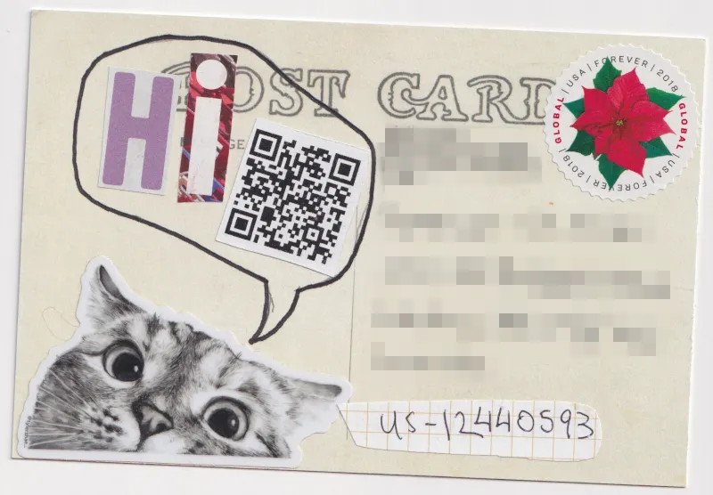 A sticker of a close up cat face partially cropped on the bottom edge of the card. A speech bubble is coming from the cat with the word 'Hi' made up of cut out magazine letters. A QR code is in the speech bubble that contains a link to a YouTube rickroll.